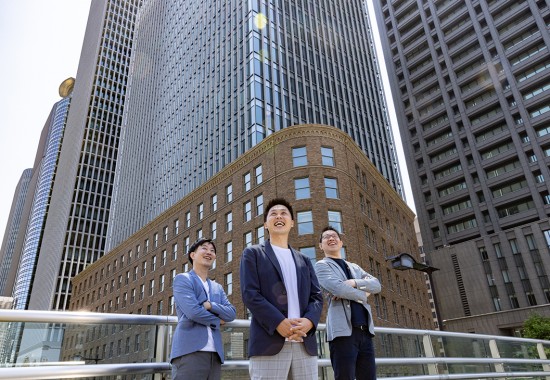 男性3人がビルの前で集合している写真