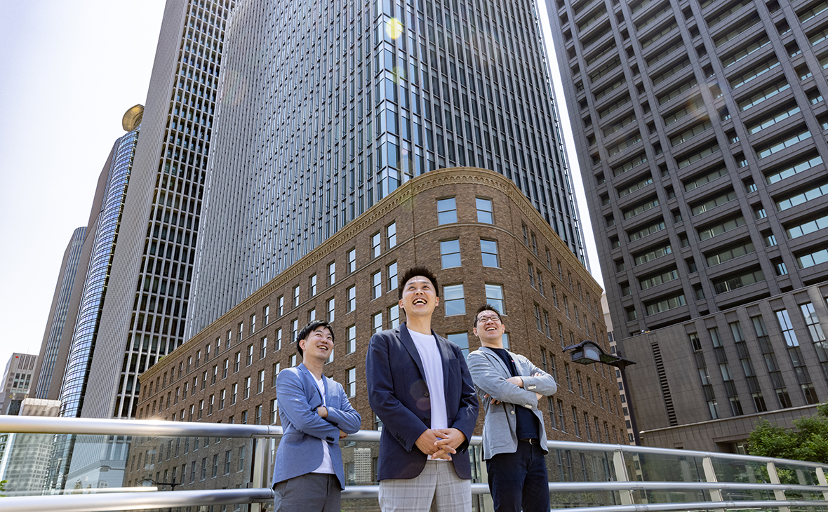 男性3人がビルの前で集合している写真